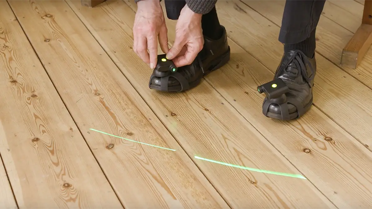 Schuhe mit Laser-Aufsatz projizieren grüne Linien auf einen Holzboden